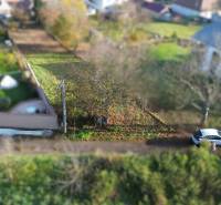 Földterületek - lakóövezet az M.H. Chvoteková utcában Dolná Krupában, zöldövezettel és parkoló autóval.