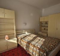 Hálószoba egy családi házban világos bútorokkal és mintás ágytakaróval.