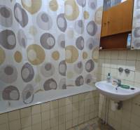 Fürdőszoba családi házban, kád függönnyel, mosdó szappannal és tükör.