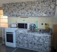 Konyha csempével, tűzhellyel és kandallóval egy családi házban, fa dekoros padlóval.