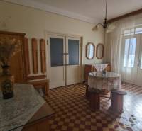 Családi ház belső tere színes csempével, virágvázával és függönyökkel.