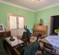 Nappali a családi házban bútorokkal, edzőfelszereléssel és zöld falakkal.