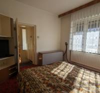 Hálószoba családi házban, televízióval és virágmintás ágyneművel.