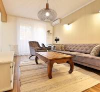 Nappali egy háromszobás lakásban, fa hatású padlóval és stílusos bútorokkal.