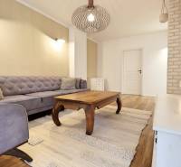 Nappali egy háromszobás lakásban kanapéval, fa asztallal és fa dekorációjú padlóval.