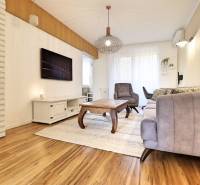 Nappali kanapéval és fotellel egy háromszobás lakásban, fa dekor padlóval.