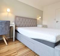 Hálószoba egy háromszobás lakásban kényelmes ággyal és fa dekorációjú padlóval.