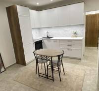 Konyha egy egyszobás lakásban fehér szekrényekkel és étkezőasztallal.