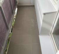 Keskeny erkély kerámia padlólappal az egyszobás lakásban.