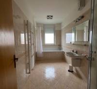 Fürdőszoba egy háromszobás lakásban káddal, üveg zuhanykabinnal és világos csempékkel.