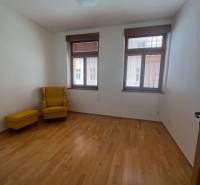 Szoba sárga fotellel és fa dekorációjú padlóval egy négy szobás lakásban.