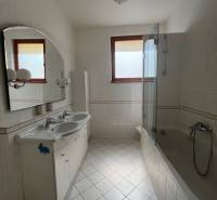 Fürdőszoba világos csempékkel, dupla mosdóval és káddal egy négy szobás lakásban.