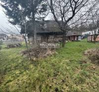 Egy régi fa ház gyümölcsfákkal körülvett füves telken, lakhatásra szánva.