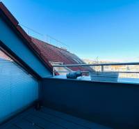 Fedett terasz egy 2 szobás lakásban, kilátással a házak tetejére és a tiszta égre.