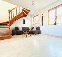 Nappali egy kétszobás lakásban csigalépcsővel és fa dekoros padlóval.