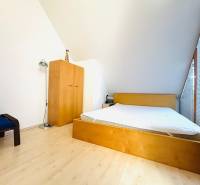 Hálószoba egy kétszobás lakásban, fa dekor padlóval, ággyal és szekrénnyel.