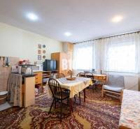 Szoba egy kétszobás lakásban szőnyeggel, asztallal, székkel és televízióval.