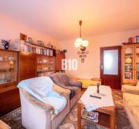 Nappali egy kétszobás lakásban kanapékkal, könyvespolccal és fa dekorációjú padlóval.