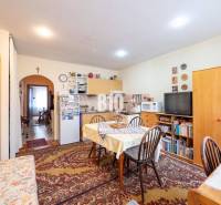 Konyha étkezőasztallal, szekrényekkel, szőnyeggel és televízióval egy kétszobás lakásban.