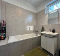 Fürdőszoba egy kétszobás lakásban káddal, mosdóval és világos csempékkel.