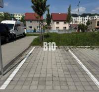 Parkolóhely Kysucké Nové Mesto-ban, háttérben lakóházak és zöldterület.