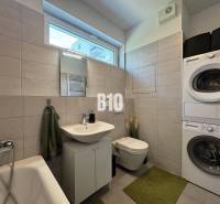 Fürdőszoba káddal, mosógéppel és szárítógéppel egy kétszobás lakásban.