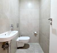 Fürdőszoba egy kétszobás lakásban WC-vel, mosdóval és semleges árnyalatú csempékkel.