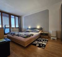 Hálószoba ággyal és bútorokkal, fa dekorációjú padló, világos árnyalatok.