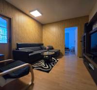 Nappali egy kétszobás lakásban, fa dekor padlóval és kényelmes ülőgarnitúrával.