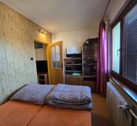 Hálószoba egy kétszobás lakásban, fa dekor padlóval, ággyal és tárolóegységgel.