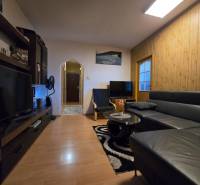 Nappali egy kétszobás lakásban, fa mintázatú padlóval és fekete kanapéval.