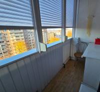 Üvegezett erkély egy 2 szobás lakásban, kilátással az épületekre, fa dekorációjú padlóval.