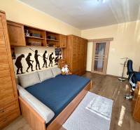 Gyerekszoba egy háromszobás lakásban, fa bútorokkal és dekoratív fallal.