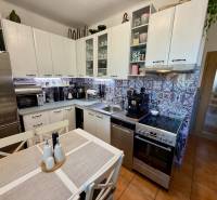 Konyha egy háromszobás lakásban fehér konyhabútorral, mintás csempével és rozsdamentes acél készülékekkel.