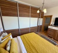 Hálószoba nagy beépített szekrénnyel, televízióval és ággyal egy háromszobás lakásban.