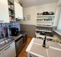 Konyha egy háromszobás lakásban fehér bútorokkal, dekoratív mintákkal és fűszertartó polccal.