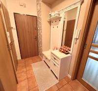 Előszoba egy háromszobás lakásban csempével, tükörrel és fogasfallal.