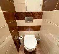 WC a háromszobás lakásban barna és bézs árnyalatú csempékkel.