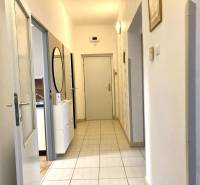 Folyosó egy 3 szobás lakásban világos csempékkel és tükörrel a falon.