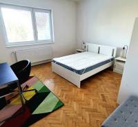 Világos hálószoba egy háromszobás lakásban, fa dekorációjú padlóval és íróasztallal.