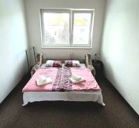 Hálószoba egy háromszobás lakásban ággyal, ablakkal és dekorációra helyezett törölközőkkel.