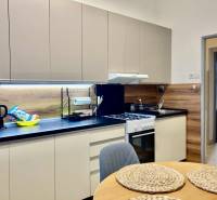 Konyha egy háromszobás lakásban, fa dekorációjú padlóval és modern felszereléssel.