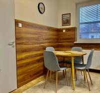 Konyha étkezőasztallal, szürke székek, fa mintázatú padló, 3 szobás lakás.