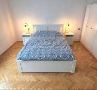 Hálószoba ággyal, éjjeliszekrényekkel és szekrénnyel, fa dekoros padlóval.