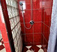 Zuhanykabin piros csempékkel és üvegfallal egy háromszobás lakásban.