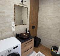 Fürdőszoba kerámia mosdóval és mosógéppel egy kétszobás lakásban, fa dekoros padlóval.