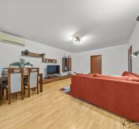 Nappali egy kétszobás lakásban, fa mintázatú padlóval és piros kanapéval.