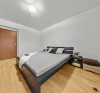 Hálószoba egy kétszobás lakásban ággyal, szekrénnyel és fa dekorációjú padlóval.