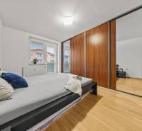 Hálószoba ággyal, beépített szekrénnyel és fa dekoros padlóval egy kétszobás lakásban.