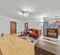 Nappali piros kanapéval és fa dekorációjú padlóval egy kétszobás lakásban.